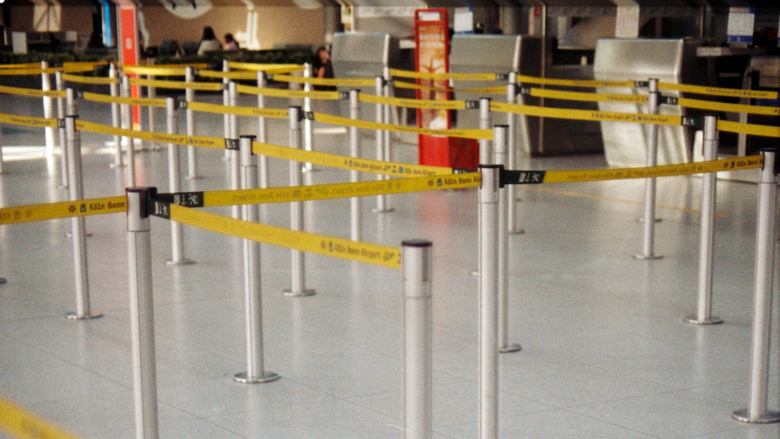 Rows of yellow retractable belt barriers forming lanes in an airport terminal
