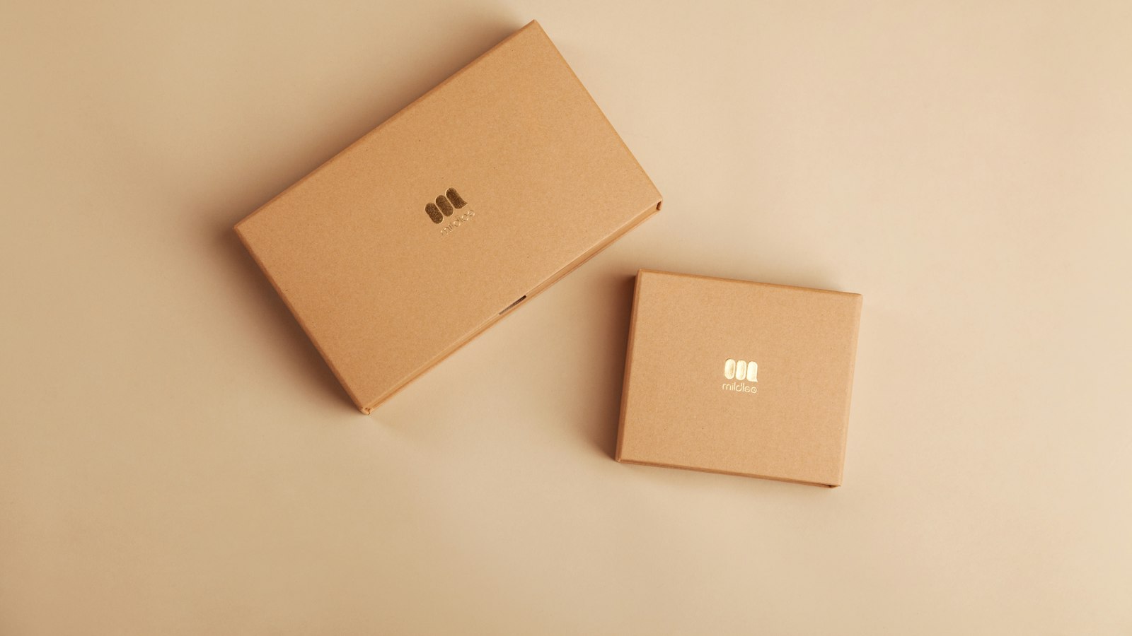 Two plain kraft cardboard boxes on a peach colored surface