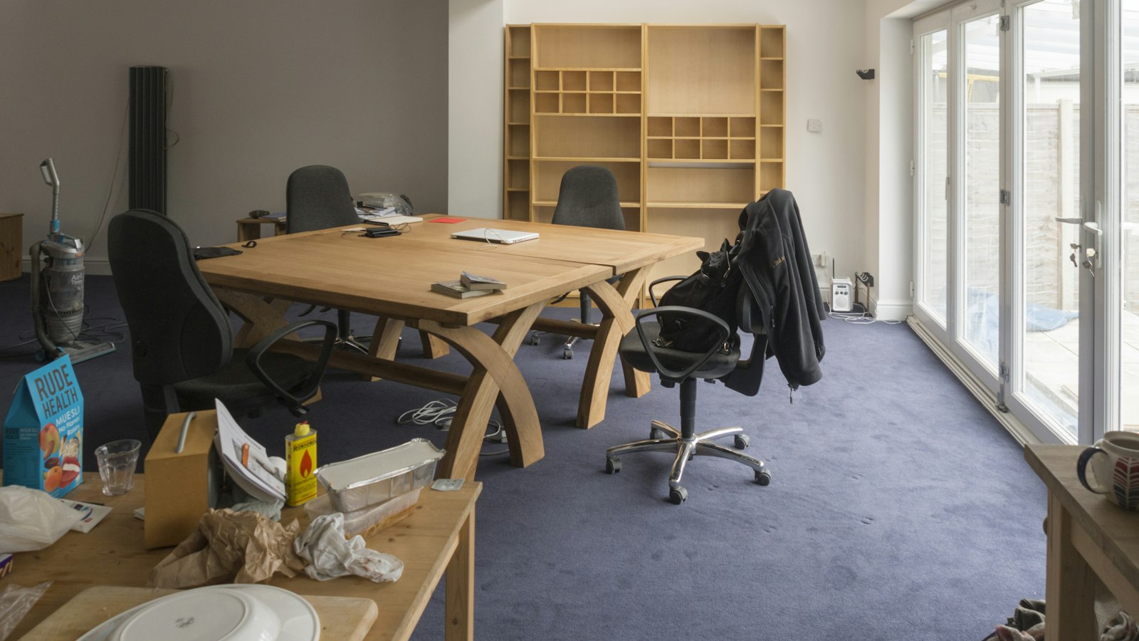 Empty office with a large wooden table, chairs and tall windows